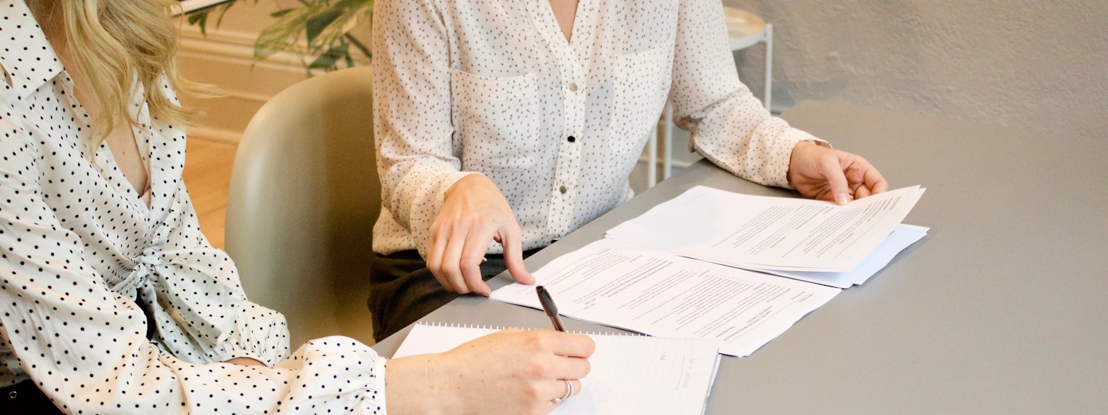 Welche Dokumente werden für die LEI-Beantragung benötigt? Zwei Frauen unterschreiben Dokumente an einem Tisch — für die LEI-Beantragung erforderliche Unterlagen